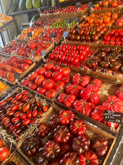Twenty-five varieties of tomato on display at Bora & Sons — cherry, beefsteak, heirloom and more, arranged in wooden crates